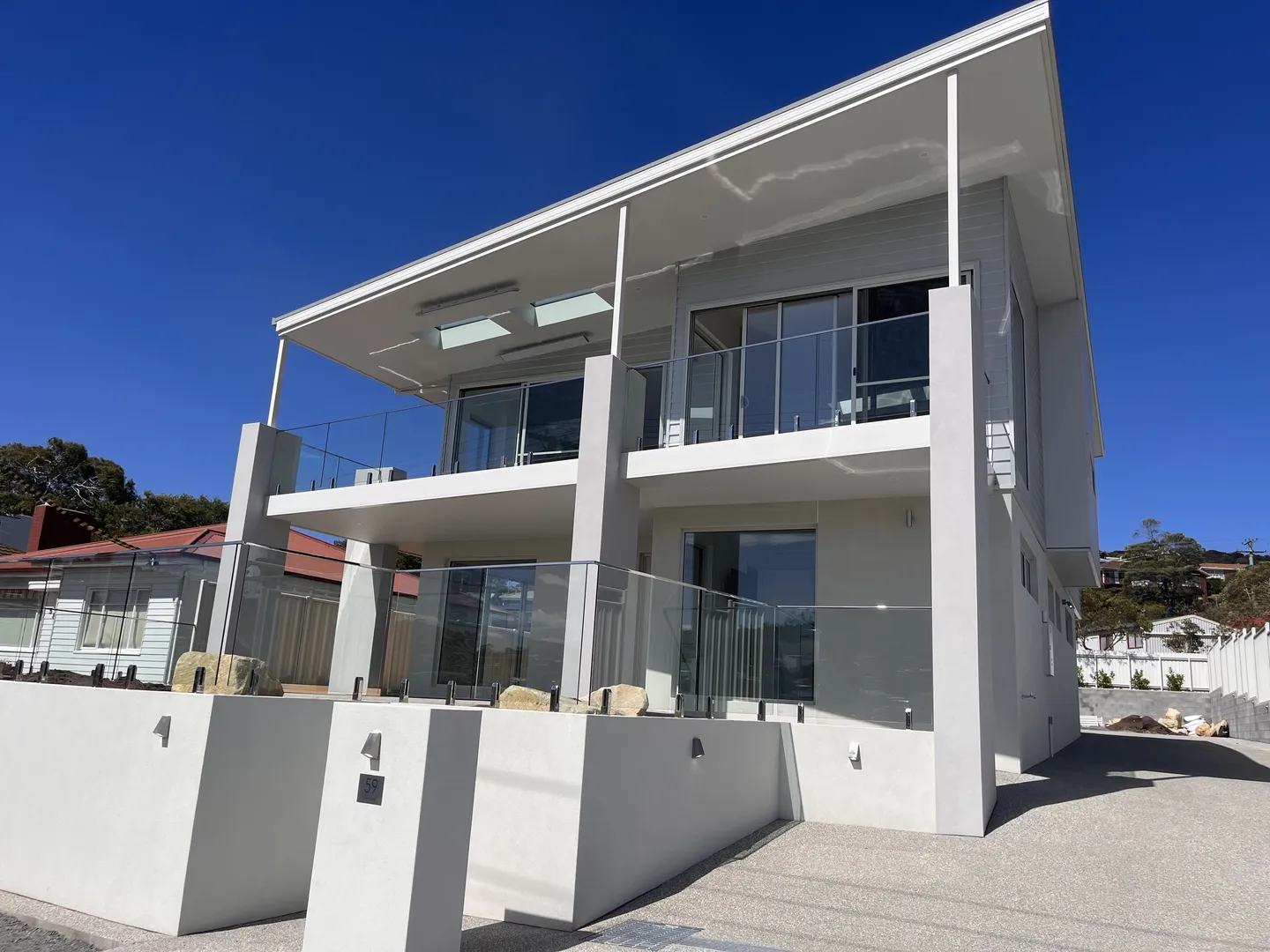 Modern two-story house with glass balcony.