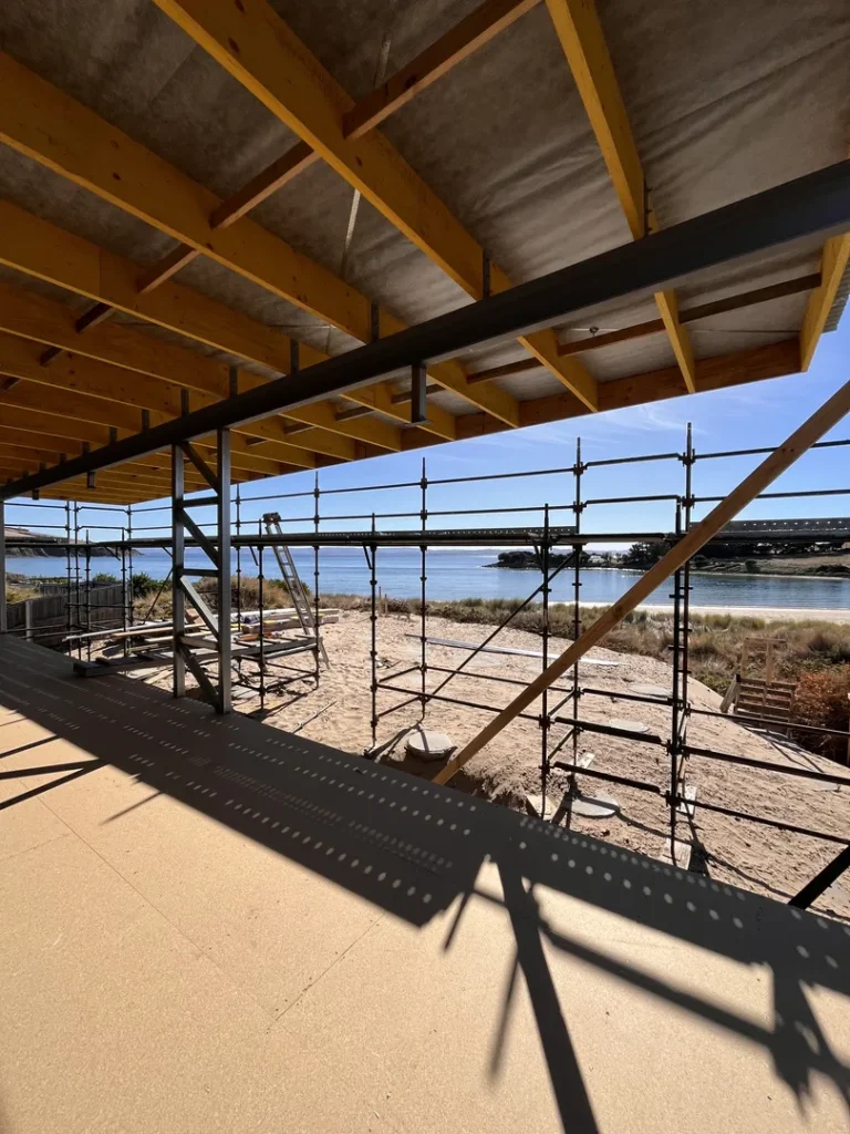 Construction site near beach with scaffolding and beams.